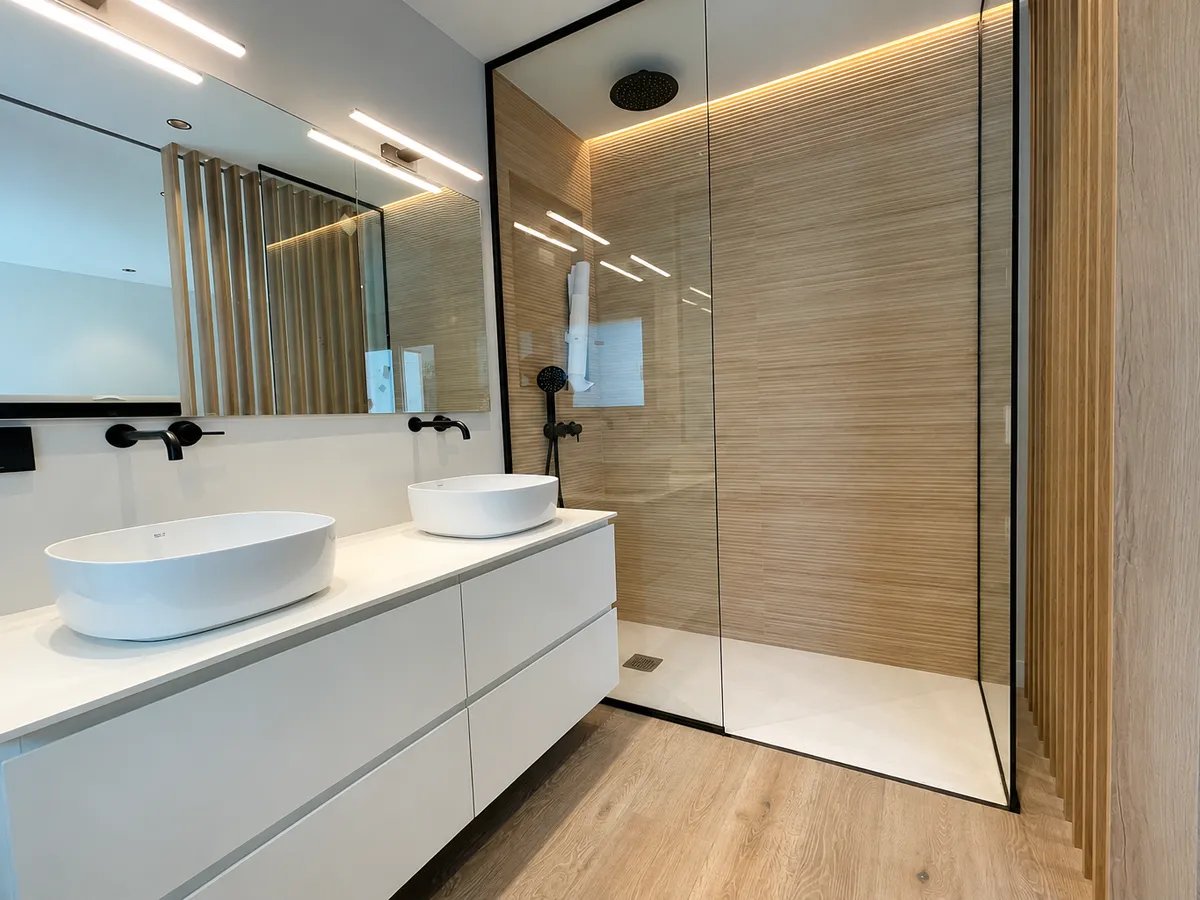 Bano reformado en Valencia con suelo y revestimiento efecto madera, mueble suspendido y ducha con mampara
