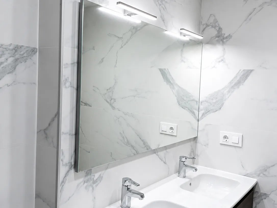 Zona de lavabo doble con espejo retroiluminado en reforma de bano en Valencia